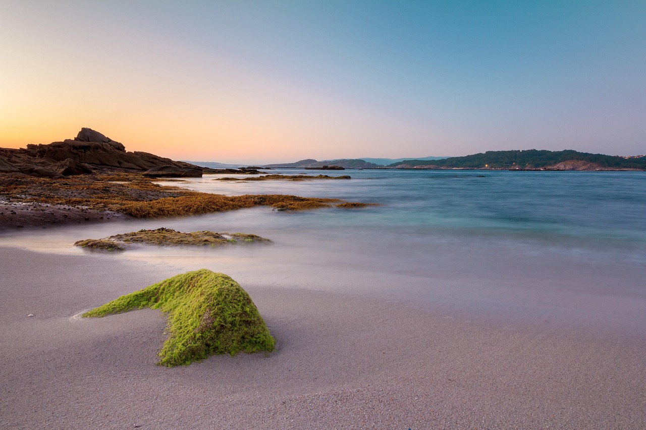 Spiaggia sarda all'alba, con acque brillanti e sabbia dorata che riflette la luce del sole.
