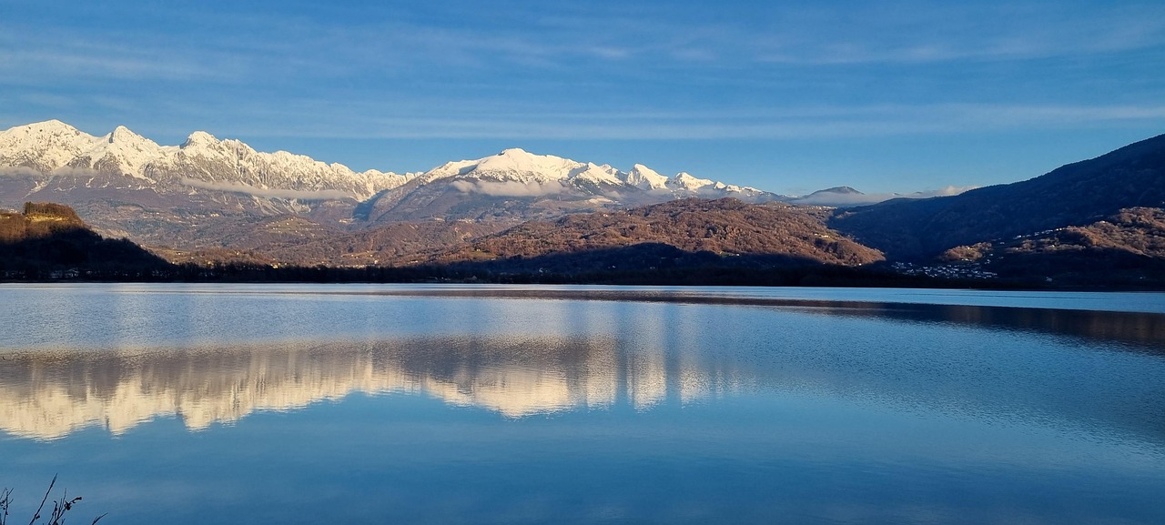 Vista panoramica del lago nascosto in Friuli, circondato da montagne e natura incontaminata.