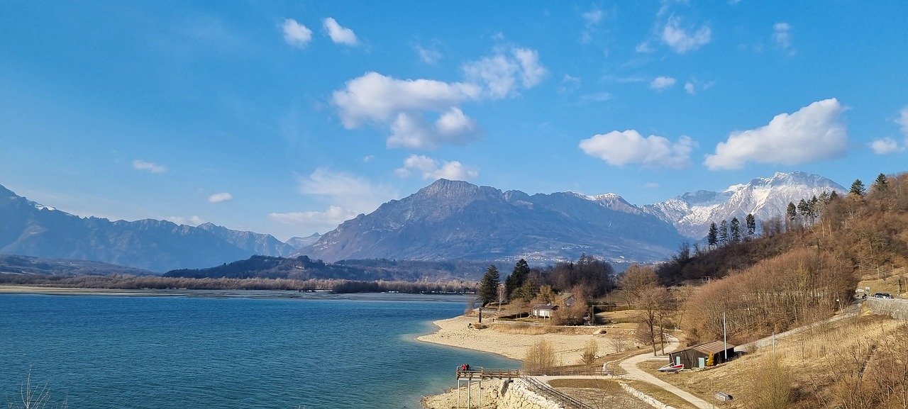 Vista panoramica del lago nascosto in Friuli, circondato da montagne e vegetazione lussureggiante.