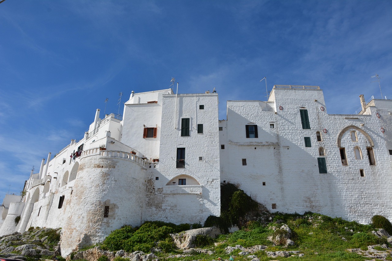 Trulli bianchi nel villaggio pugliese, circondati da natura e vista sulle spiagge nascoste.