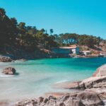 Panorama di una splendida località balneare francese con spiaggia, mare cristallino e palme.