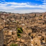 Panorama di una città italiana in declino, con edifici abbandonati e natura che riacquista spazio.