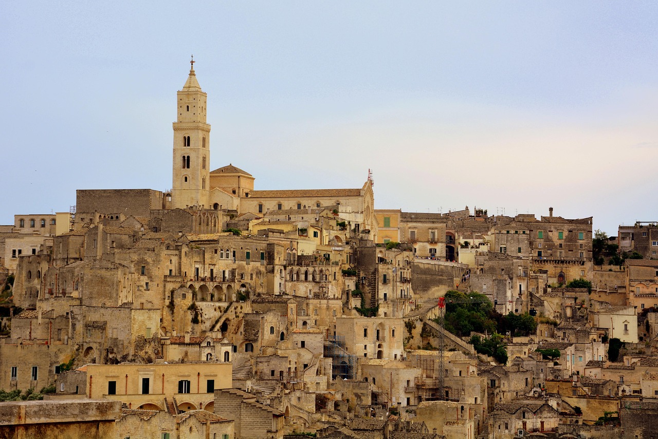 Vista panoramica dei Sassi di Matera, con le antiche abitazioni scavate nella roccia e il cielo blu.