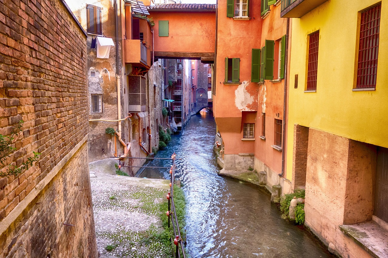 Vista panoramica di Bassano del Grappa con il ponte degli Alpini e un bicchiere di spritz in primo piano.