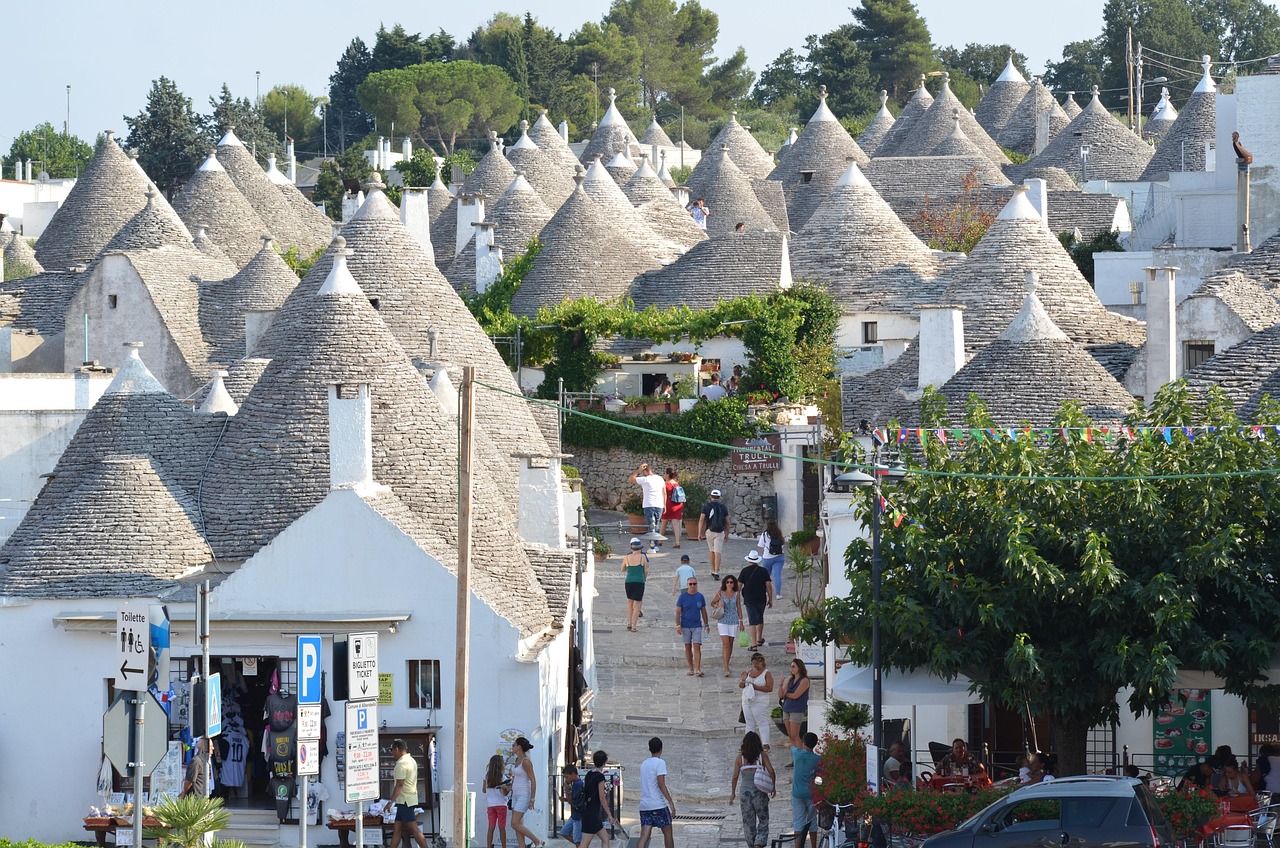 Trulli bianchi e caratteristici nel borgo pugliese, con ristoranti tipici in vista e ambiente suggestivo.