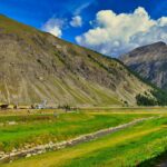 Panorama mozzafiato della Valtellina, con montagne e valli verdi sotto un cielo sereno.